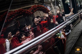 A documentary-style photograph captures a poignant moment as a bride says goodbye to her relatives and friends at a home in Fujian, China. The image portrays the emotional farewell before the wedding ceremony.
